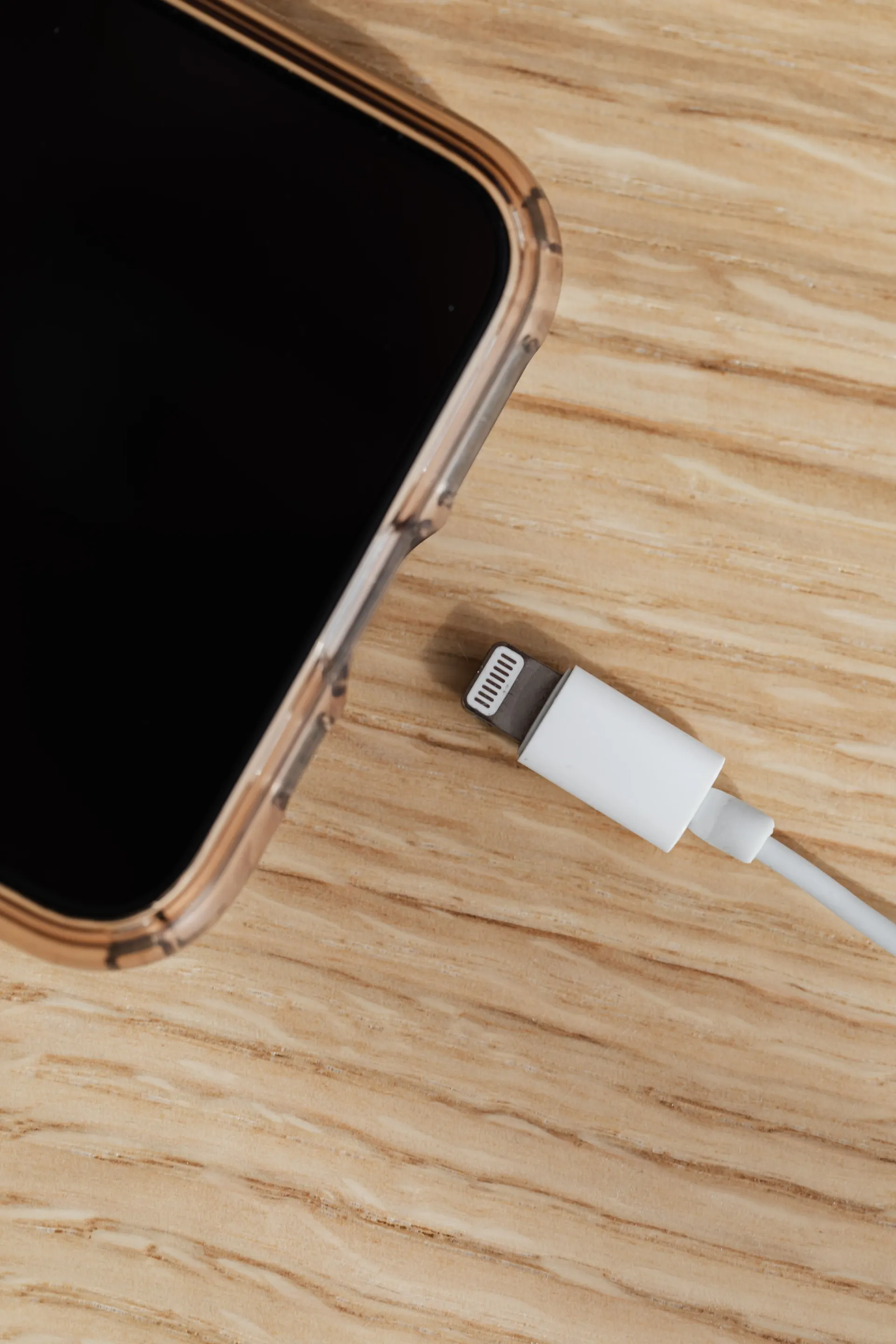 Cabo Lightning branco sobre uma mesa de madeira, acessórios Apple em Curitiba