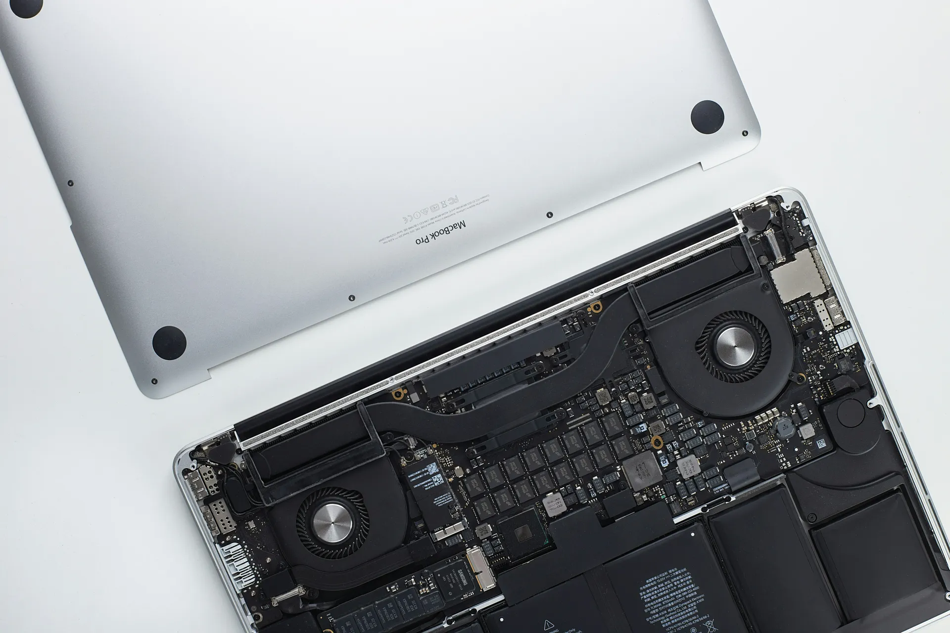MacBook Pro aberto, com a tampa inferior removida, mostrando placa lógica, ventoinhas e bateria, conserto de MacBook em Curitiba